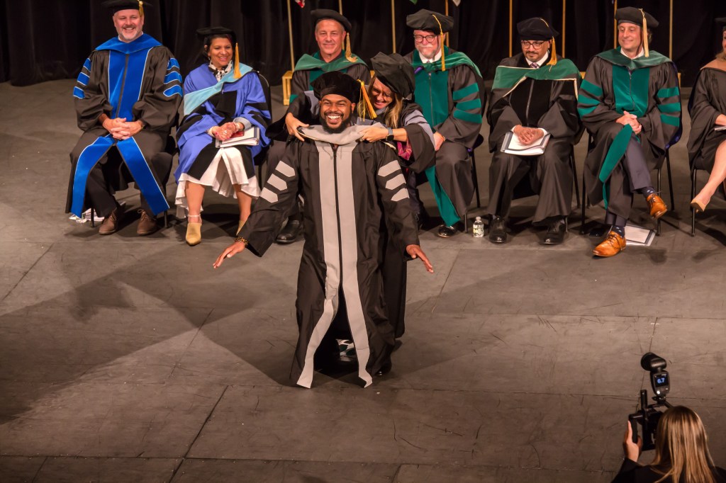 New SMU Veterinary Graduate receives his robe during commencement